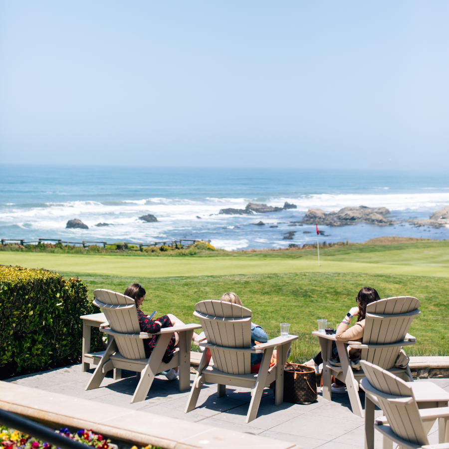 Guests sitting on wooden chairs overlooking the Pacific Ocean at the Ritz-Carlton, Half Moon Bay in California