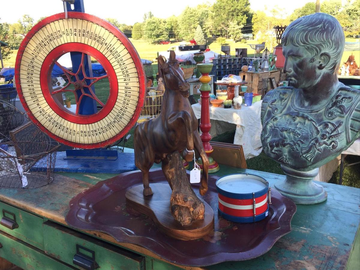 A bust of a man, a horse statue, and a wheel with numbers at the Burlington Antique Fair