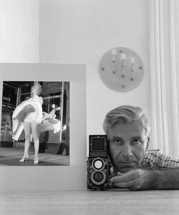 Bruno Barnard with camera next to his famous image of marilyn monroe with white dress lifted.