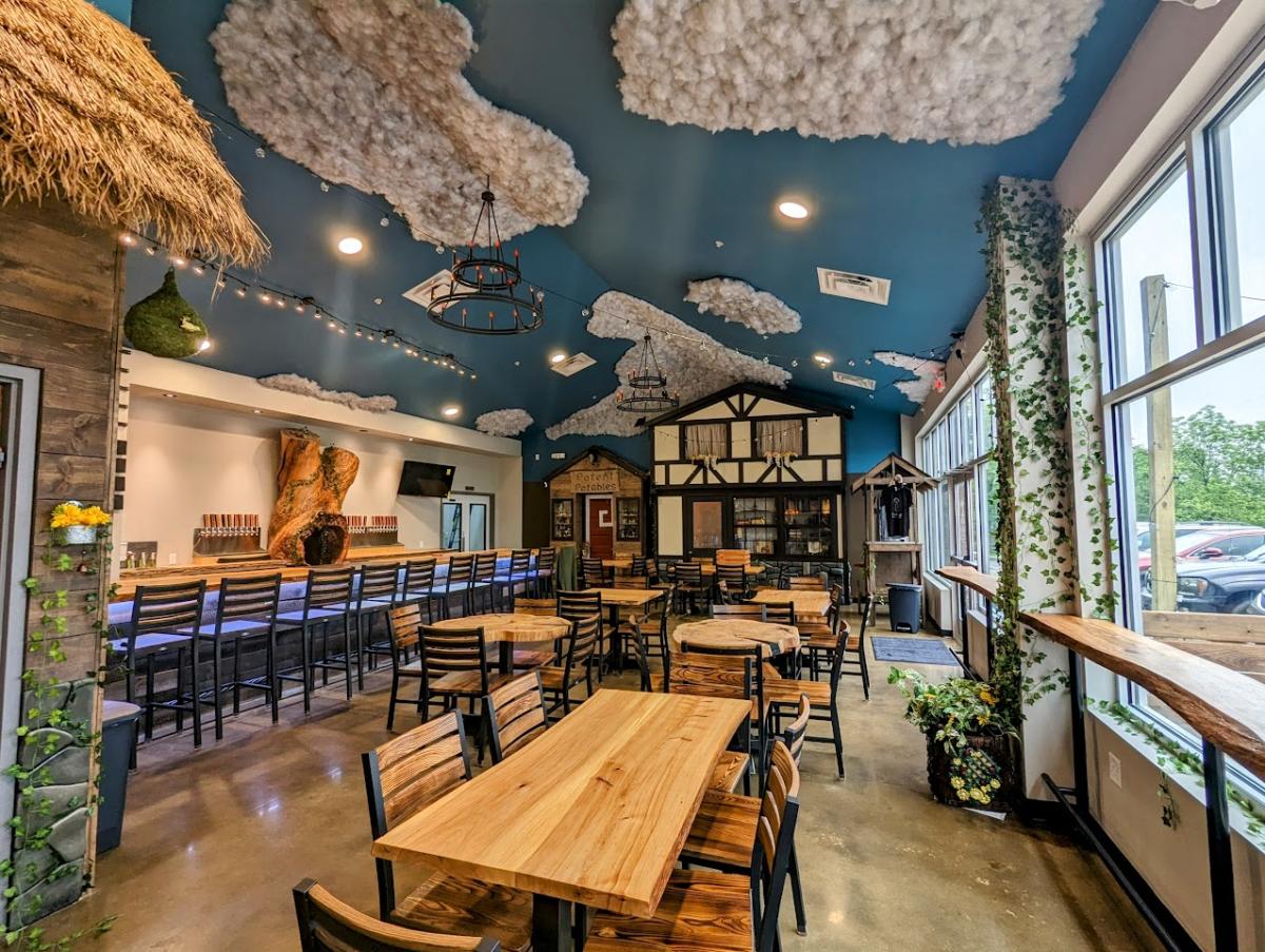 Image is of inside Fabled Brew Works where you can see the bar, tables and chairs, clouds on the ceiling and chandilers.