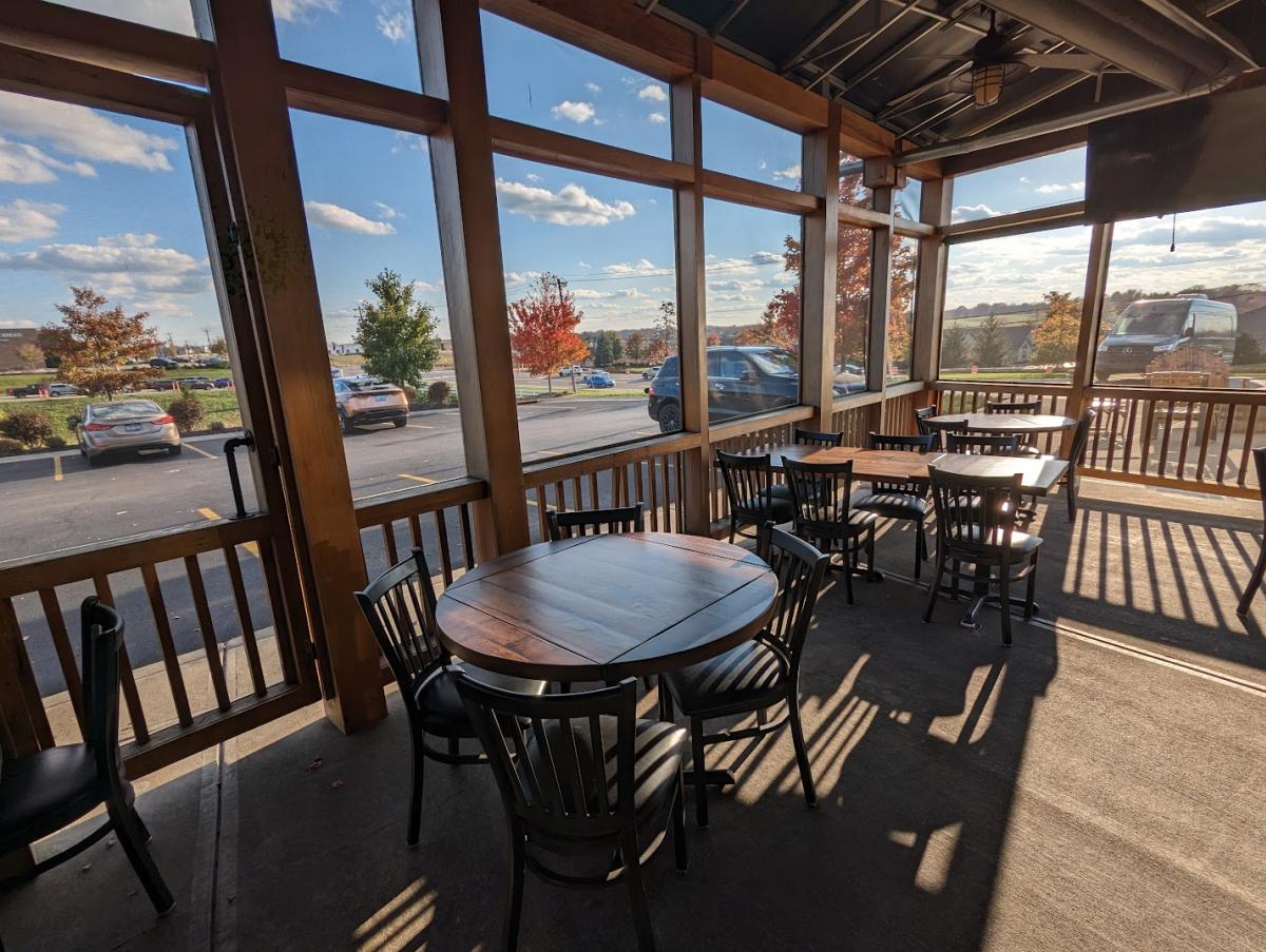 Image is of a screened in patio with tables and chairs for diners to enjoy.