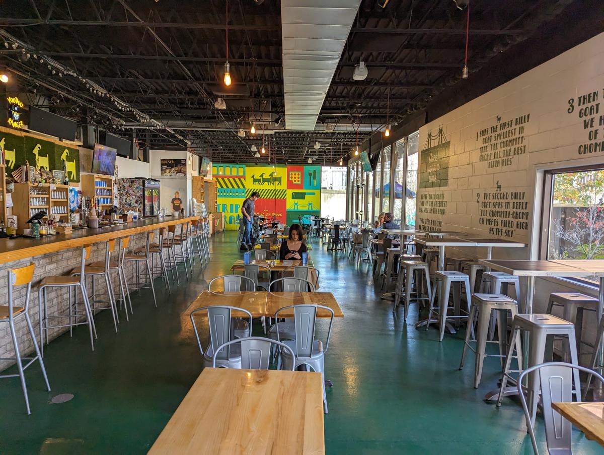 The image is of the dinning room in The Gruff with tables and chairs and a bar on the left.