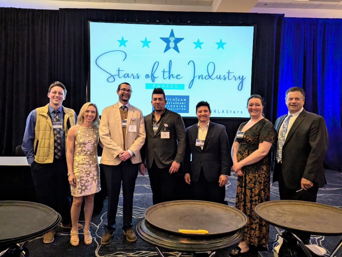 seven people stand in formal wear smiling for a photo