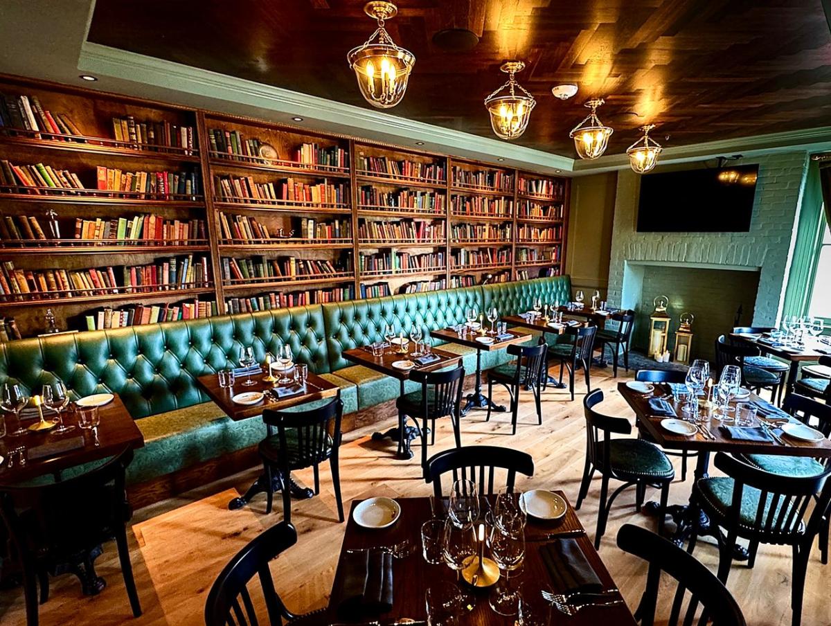 Tufted green leather banquette and floor-to-ceiling bookshelves inside Shutters on King Street in Leesburg