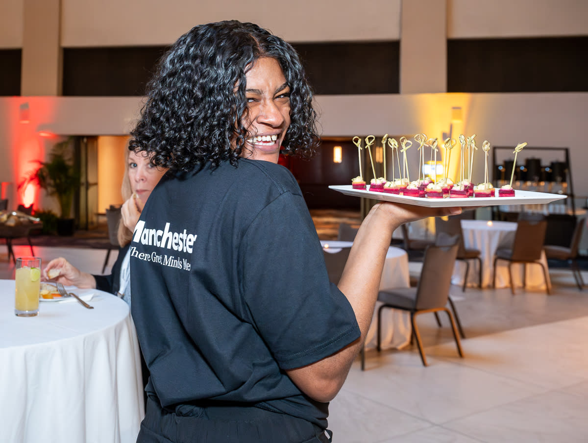 Bar staff at a cocktail reception wears a Manchester branded t-shirt