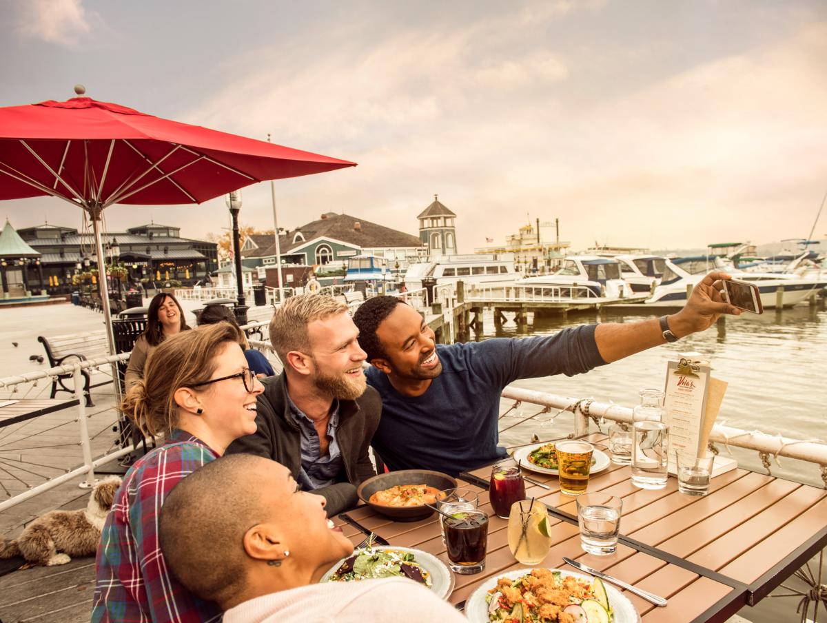 a group of LGBT friends enjoys a meal on a wharf