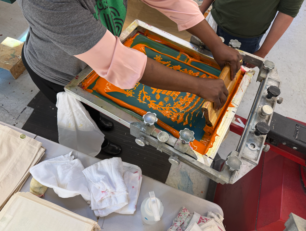 A Kei & Molly employee screen prints a tote bag.