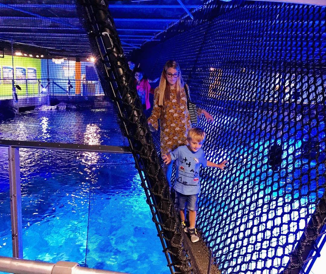 A young boy and a woman walk across the suspended Shark Bridge over a shark tank at the Newport Aquarium in Newport, Ky.