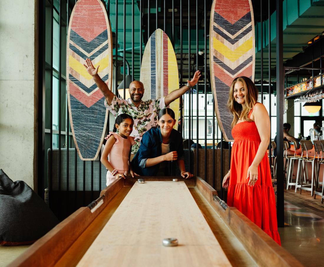 Family playing shuffle board inside of a hotel