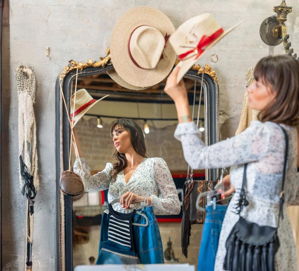 A woman trying on a cowboy hat in the mirror while shopping in the Gruene Historic District.