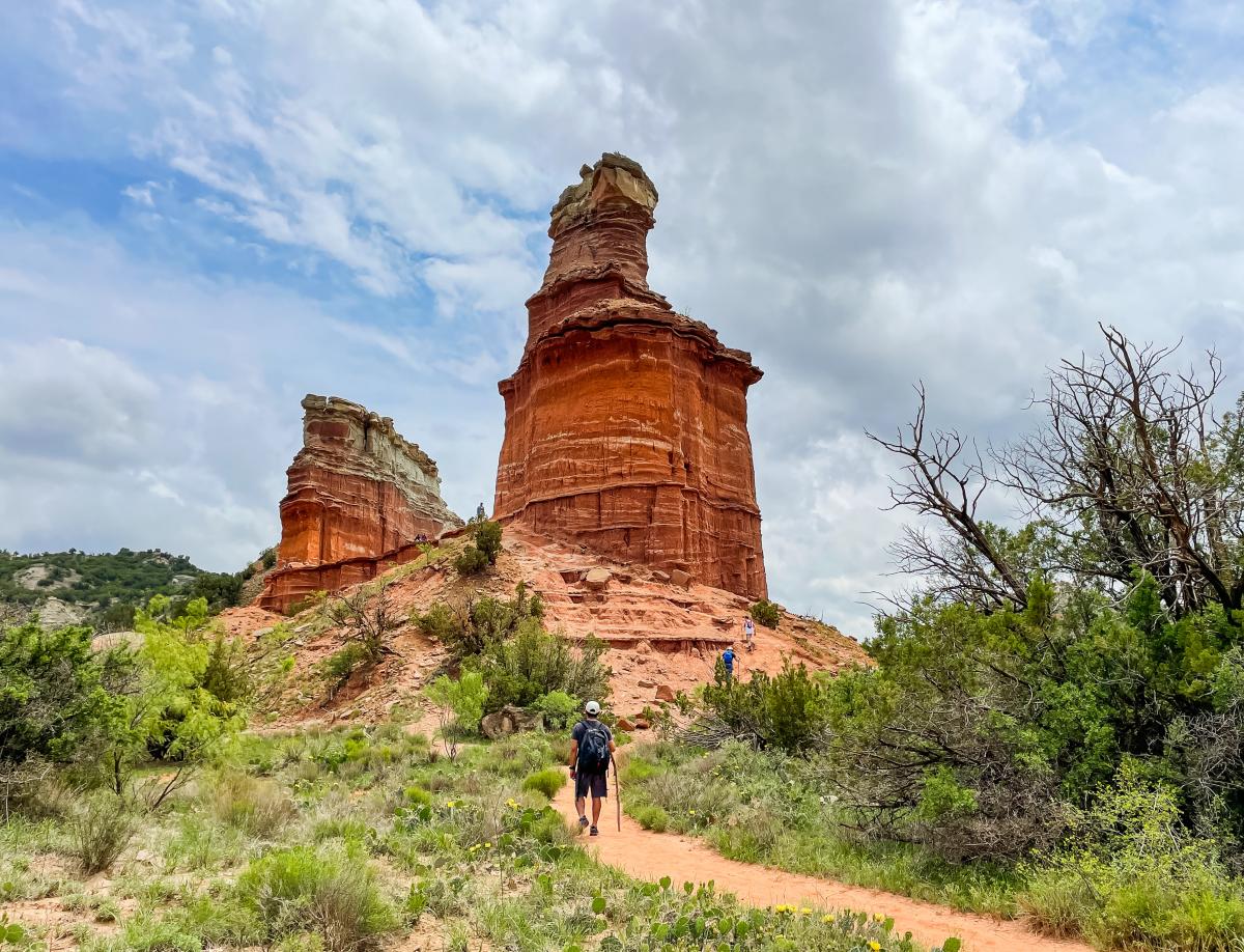 Man walking up to the beautiful red sandstone lighthouse rock structure (hoodoo) on a sunny day