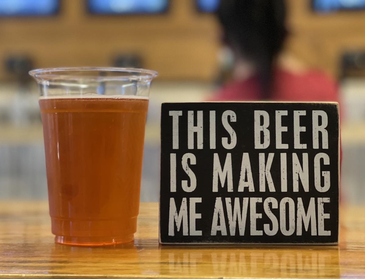 beer next to sign saying this beer is making me awesome