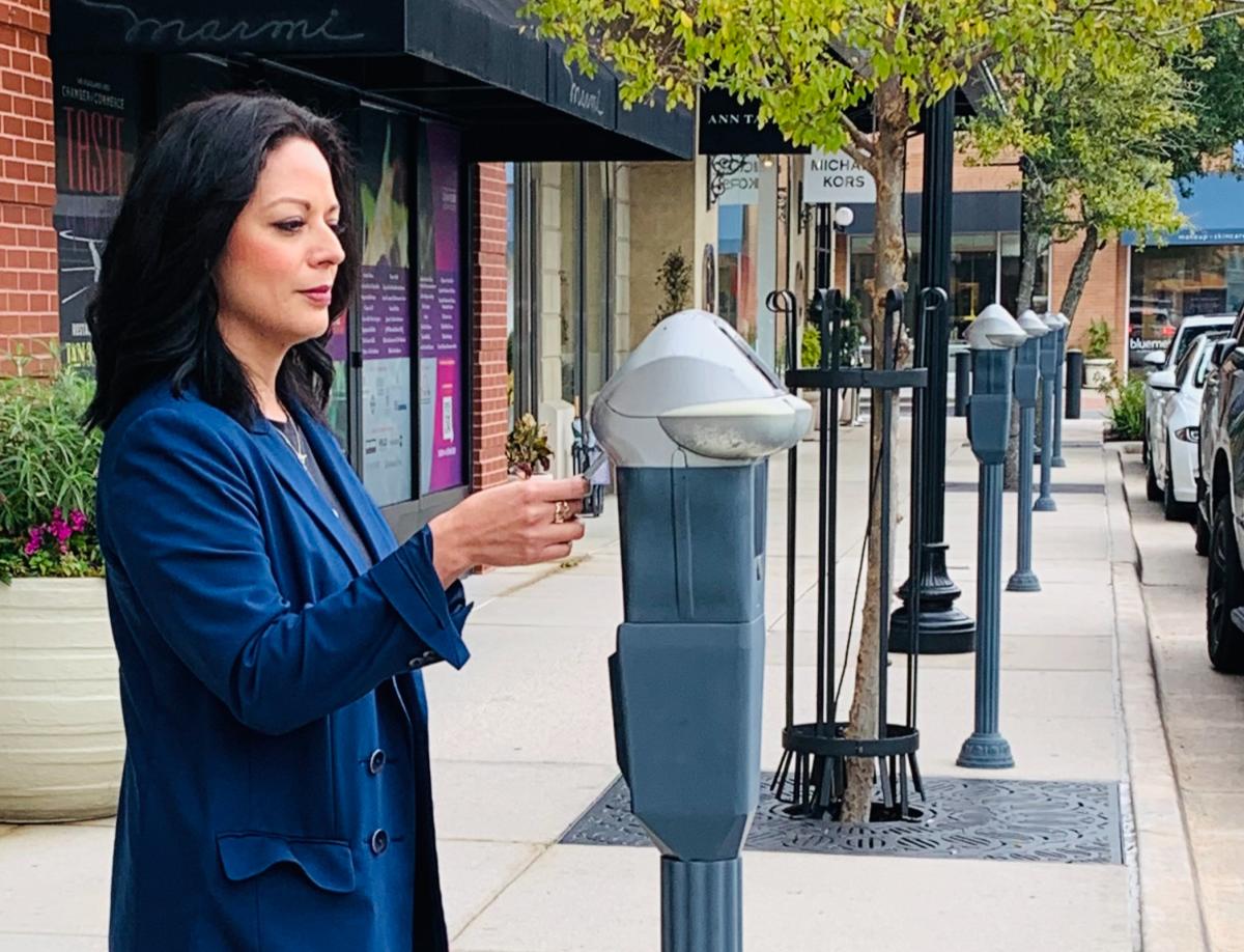 A woman with dark shoulder-length hair and a dark blue jacket, Sonia Guerrero, uses a parking meter outside the Sur La Table on Market Street.