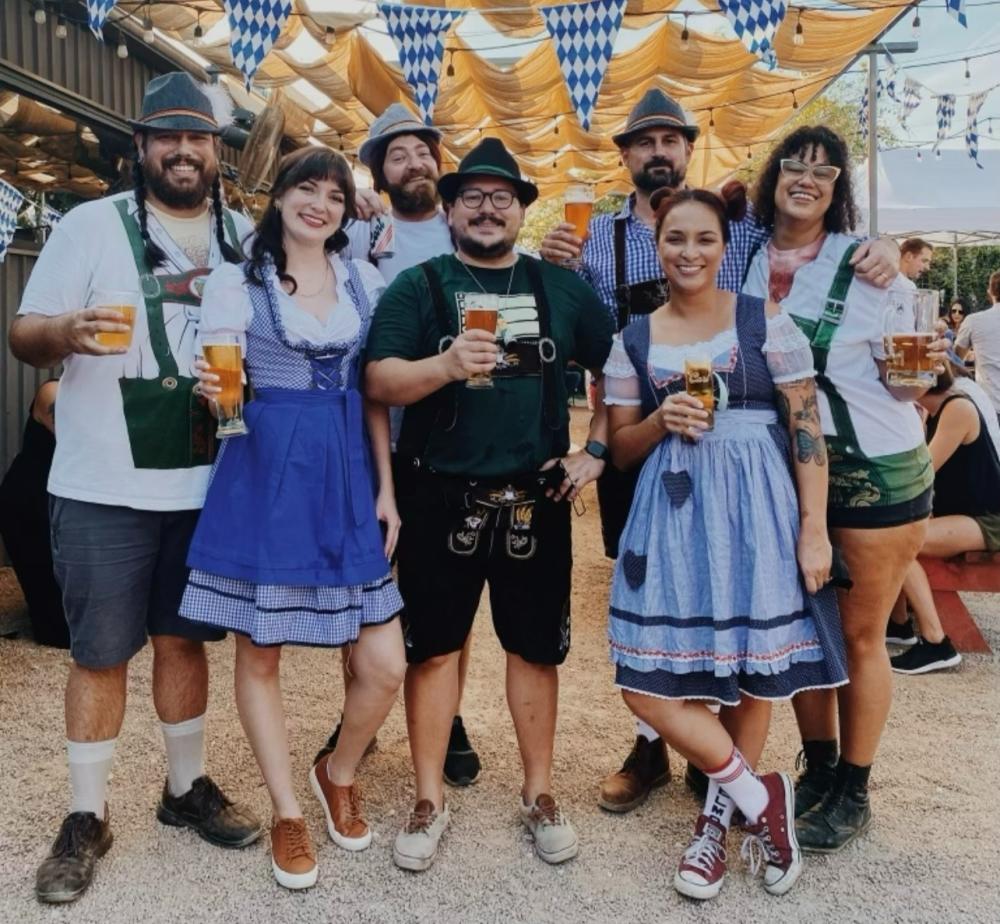 Group of people dressed in lederhosen and dirndles celebrating oktoberfest at St. Elmo Brewing.