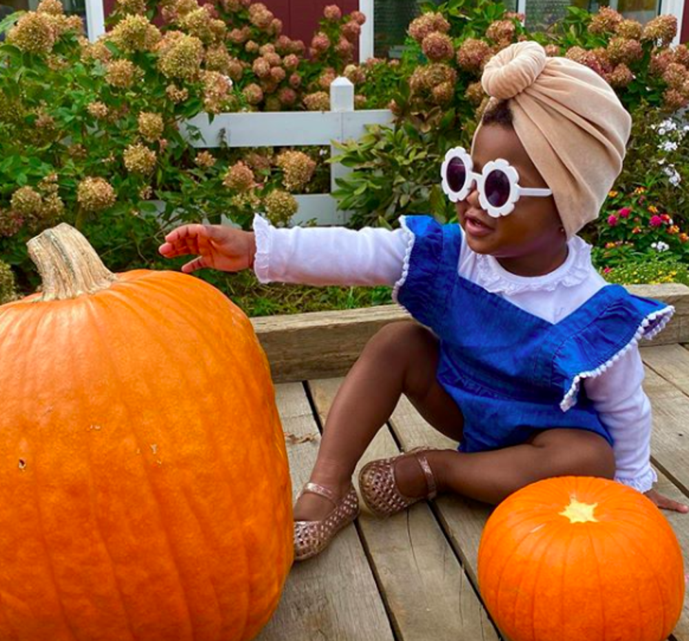 A little girl in sunglasses with a pumpkin at terhune orchards