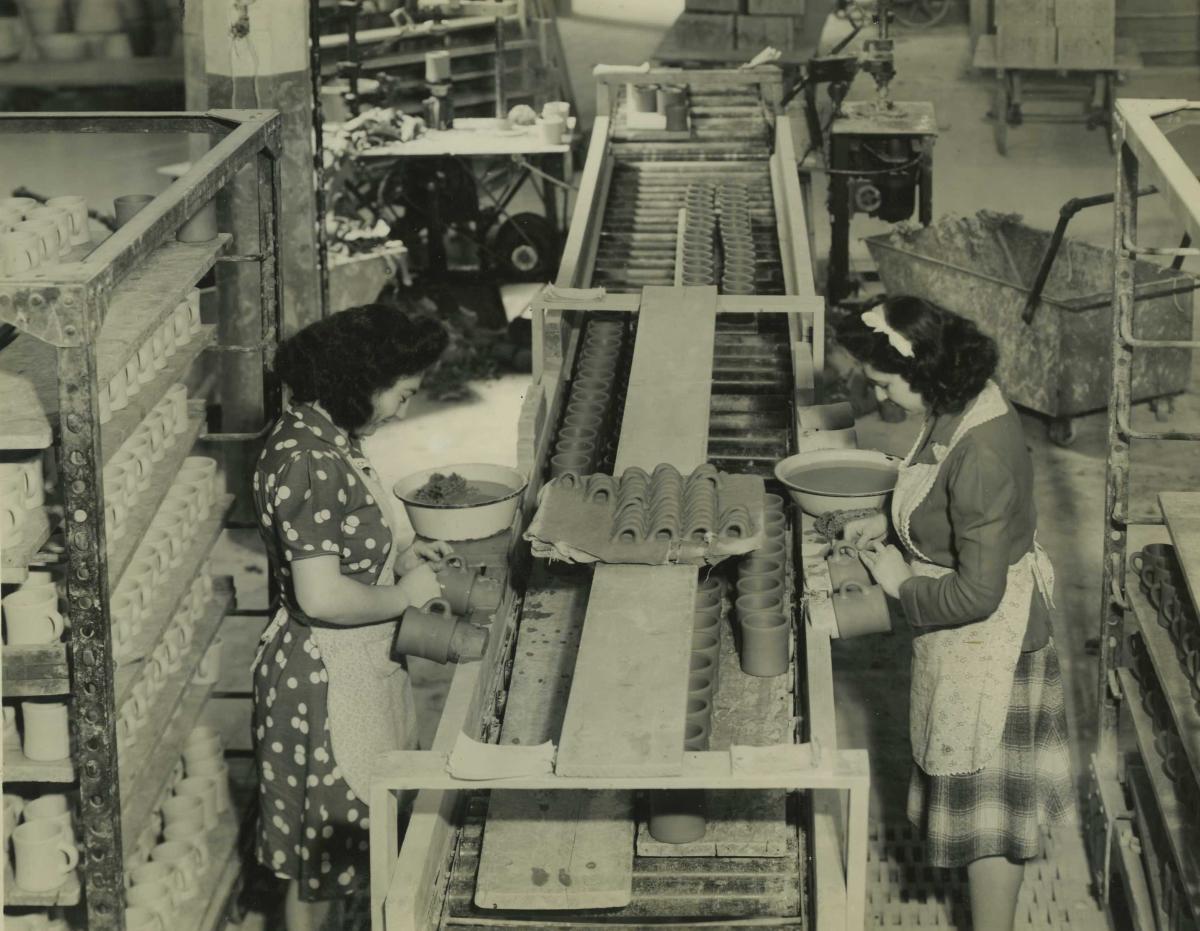 Two women work on factory line putting handles on mugs at Victor Insulators