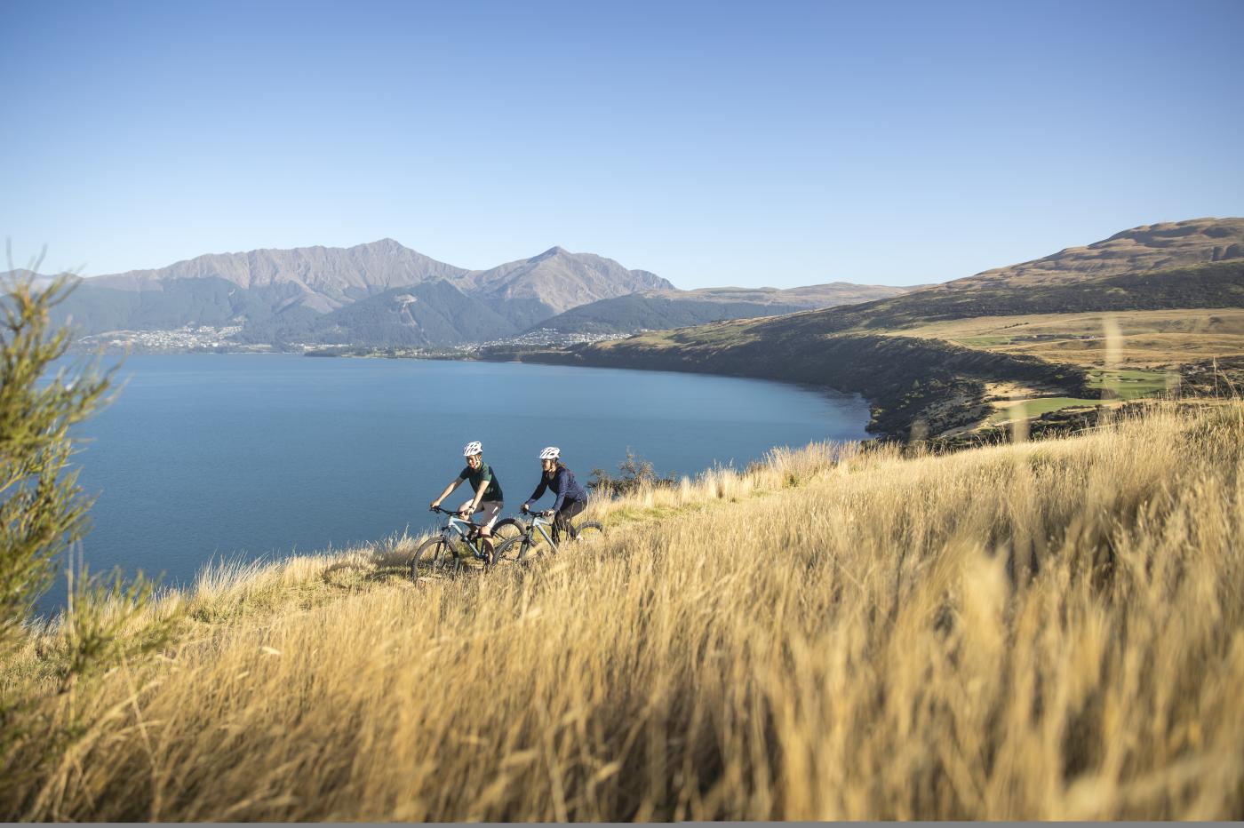 Couple biking along the lake side on the Jack's Point trail