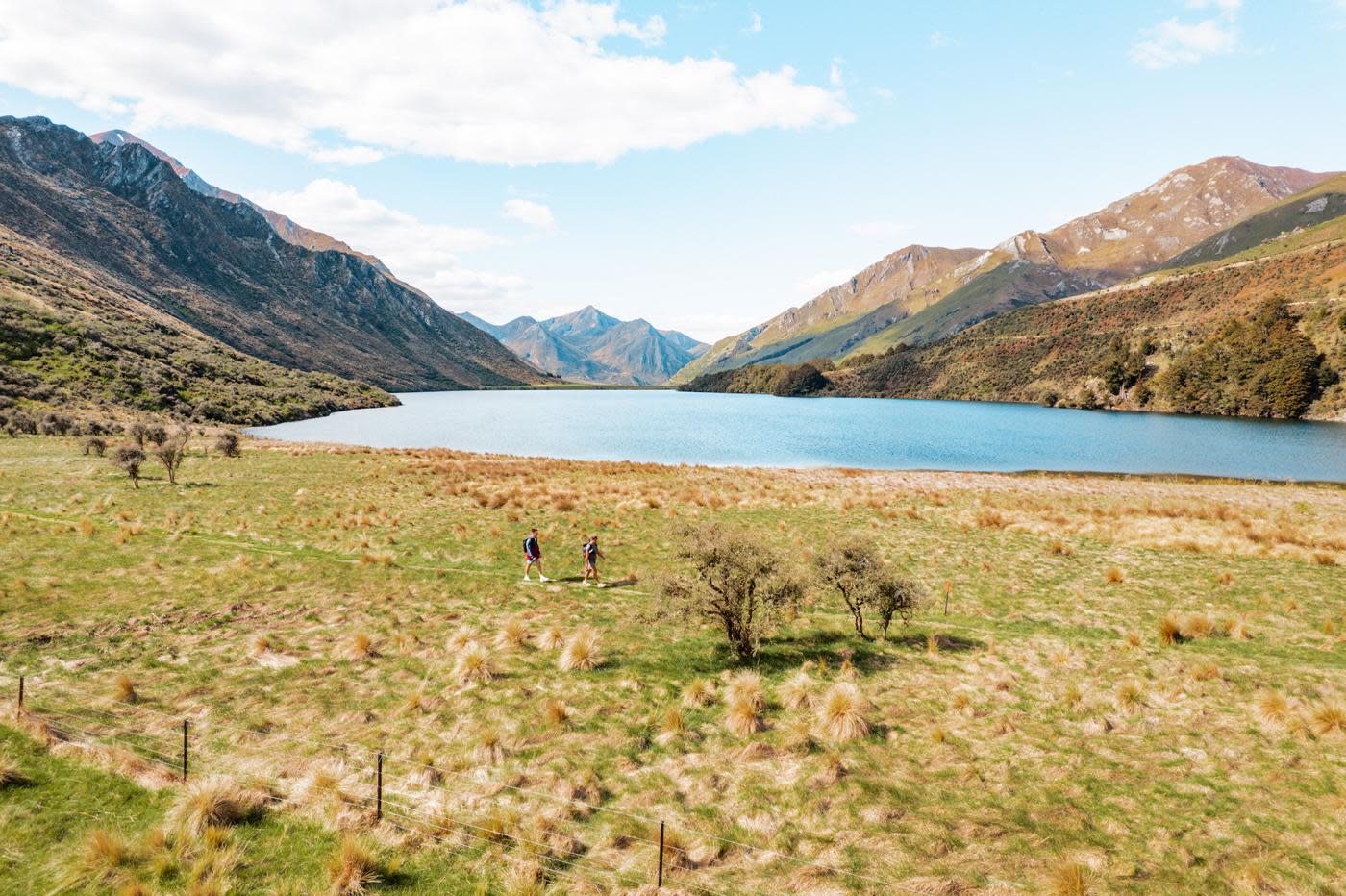 Two people walking Moke Lake Loop Track with lake and mountains in view