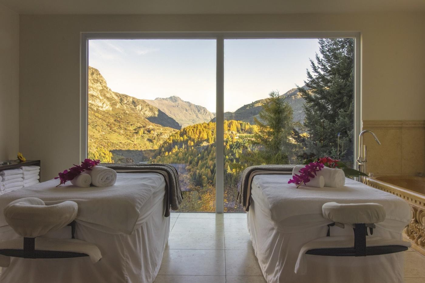 Two massage beds looking out through a huge window with mountain views