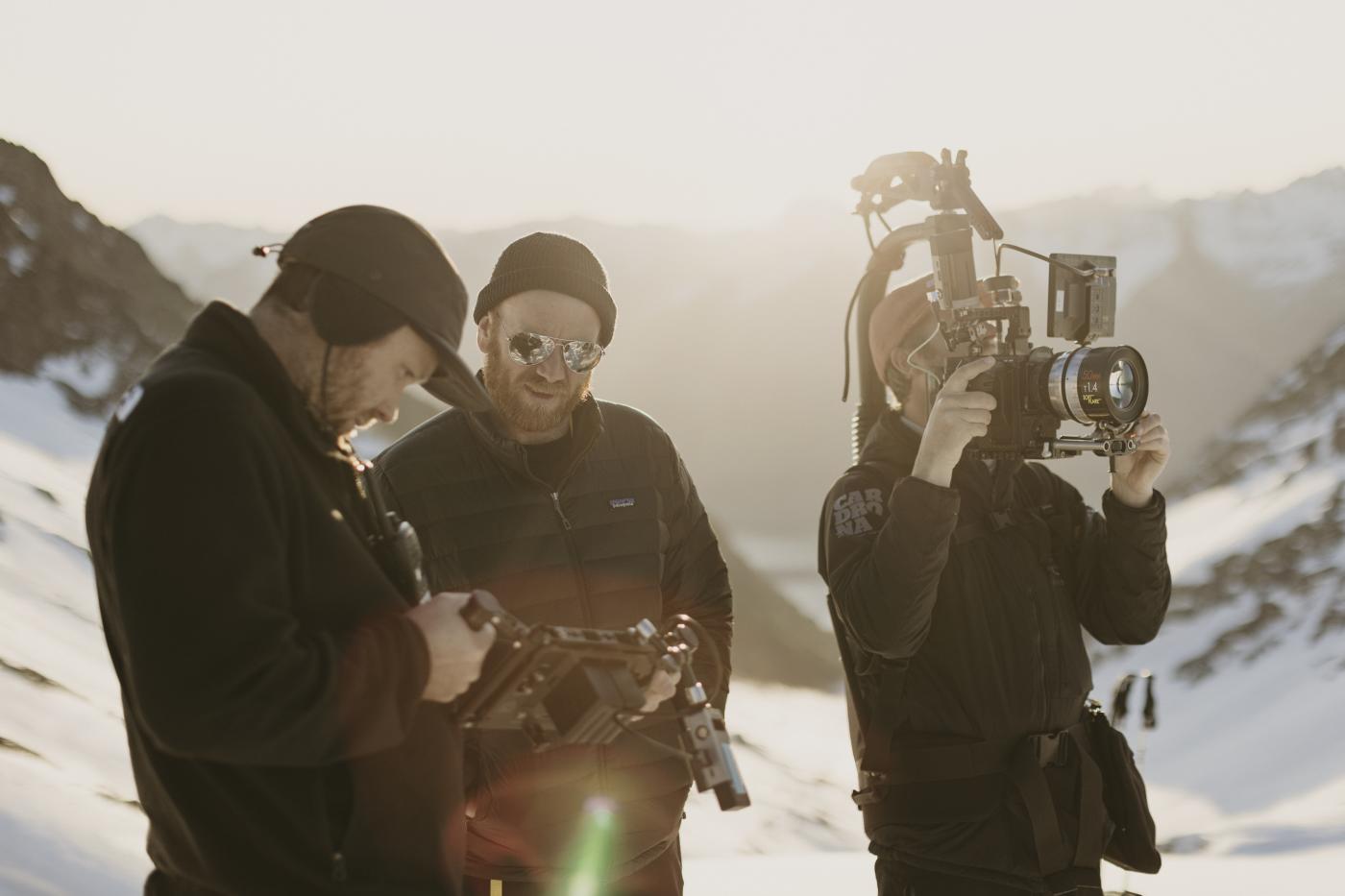 Three camera crew filming on top of a mountain