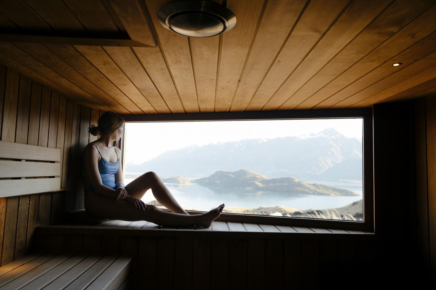 Person sitting in sauna with views of lake and mountains