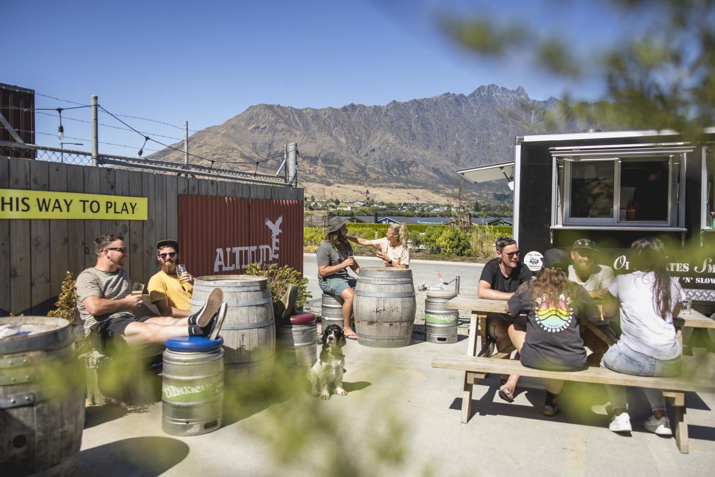 People sitting in the outdoor beer garden at Altitude Brewing with the Remarkables mountains in the background