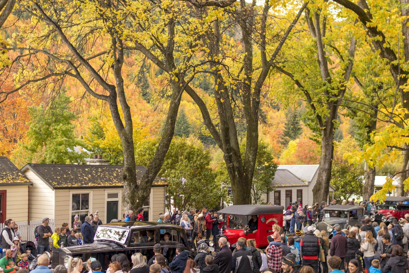 People watching the Arrowtown Autumn Festival Parade underneath colourful trees