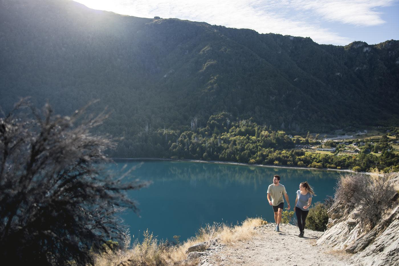 Two people walking to the top of Bob's Cove with views of the turquoise bay behind them