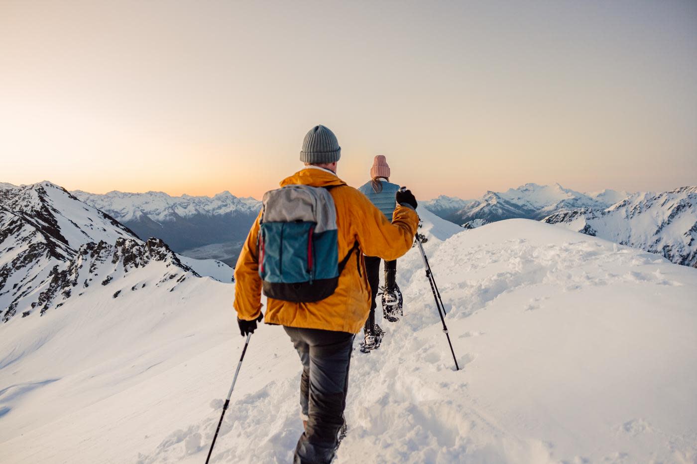 Point of view image with two people snow shoeing surrounded by snow covered mountains