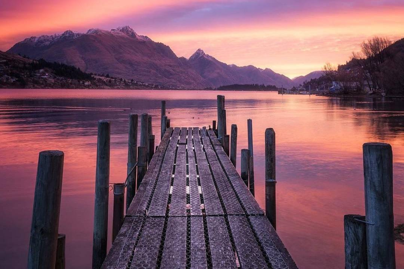 Pink and purple sunrise on lake with jetty in forefront