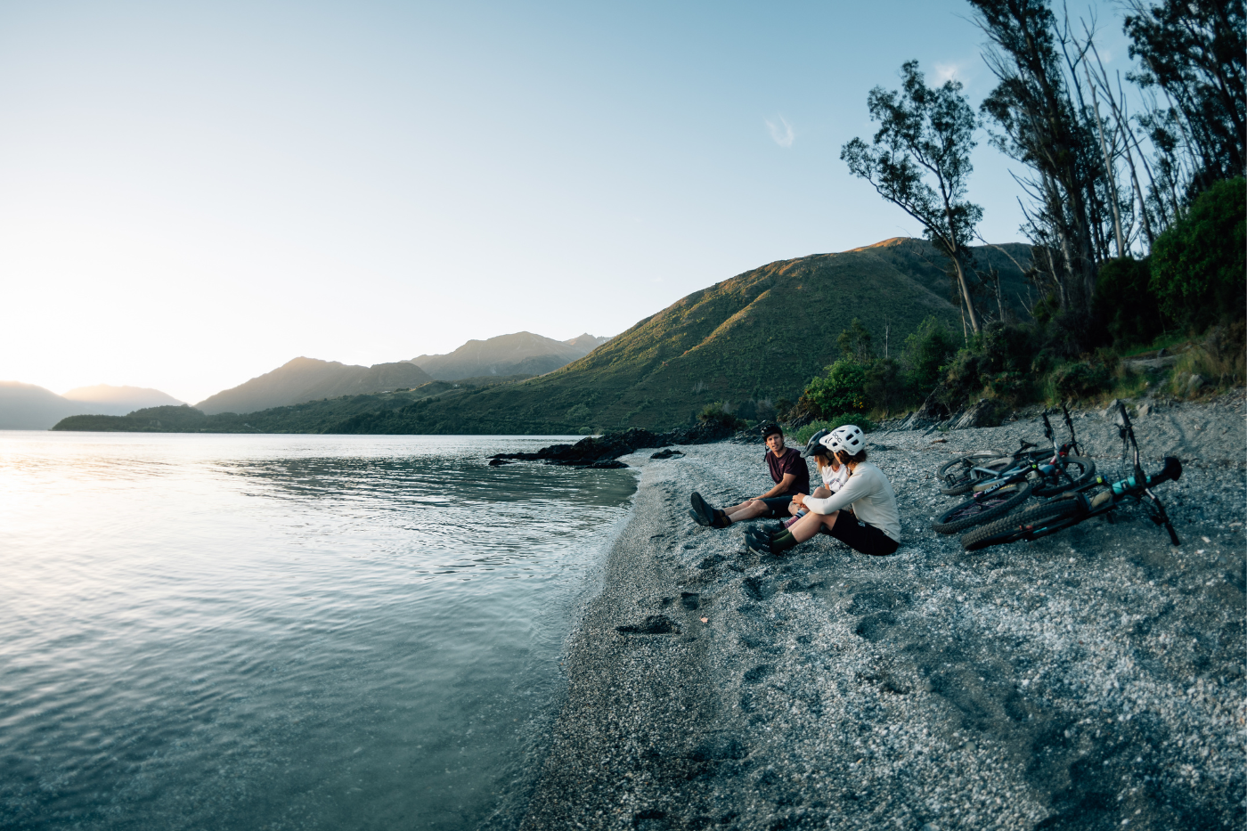 Bike riders sitting by lake at dusk