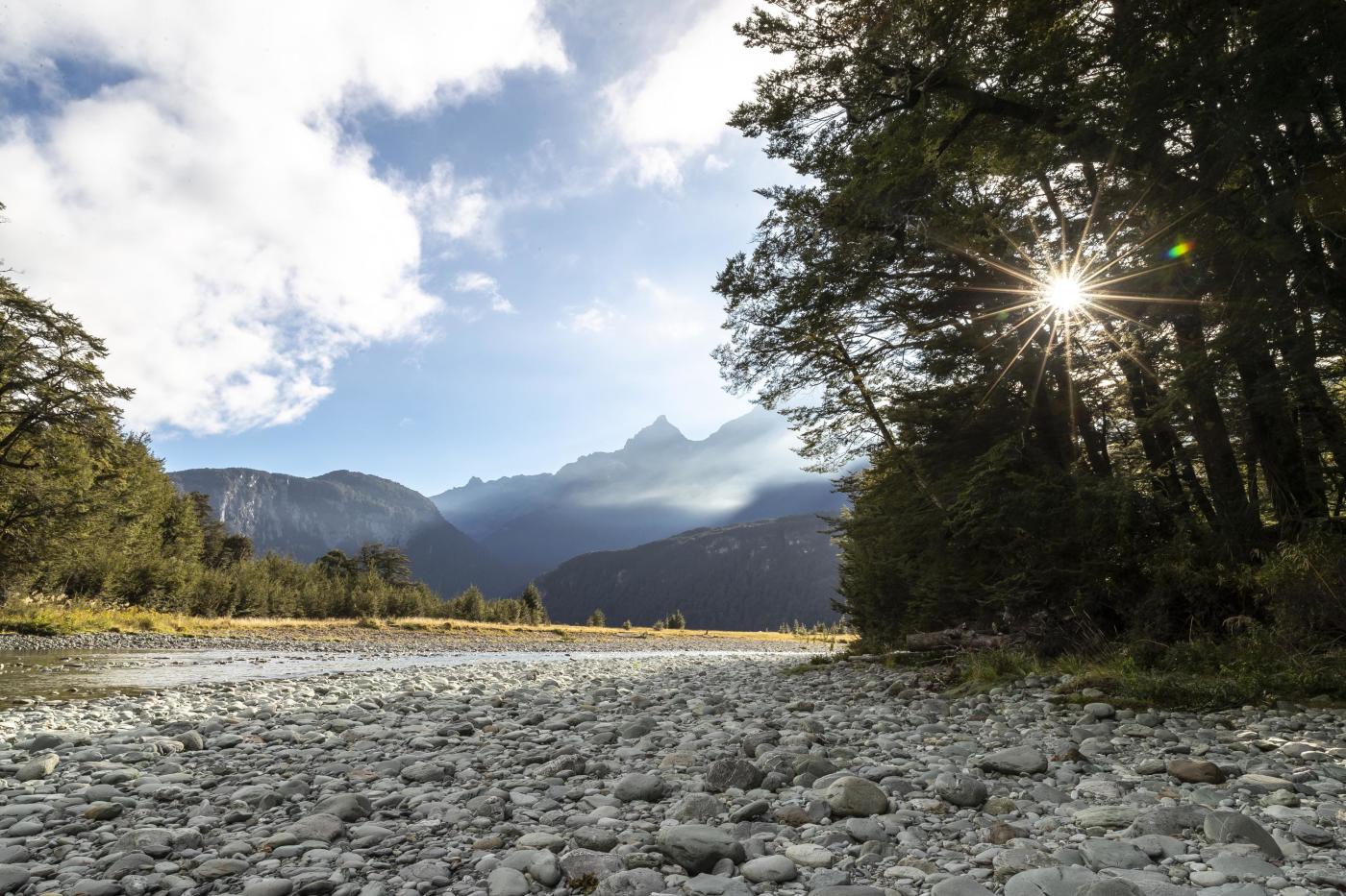 Scenic photo of a river and mountains from a rocky shore