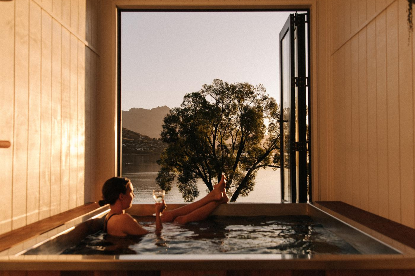 Woman relaxing with a glass of win in a hot tub at Driftaway, Queenstown