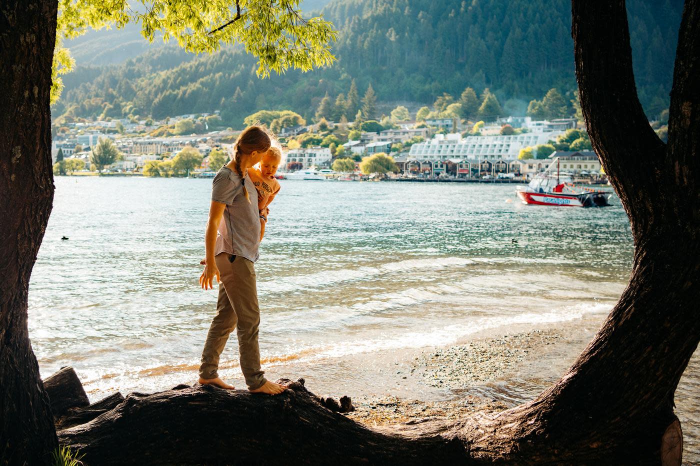 Family walking along the lake at Queenstown Bay in summer