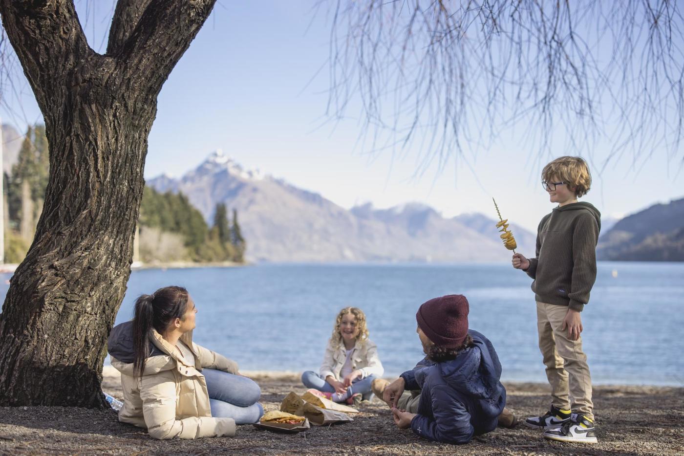 Family eating fish and chips at Queenstown Bay beach