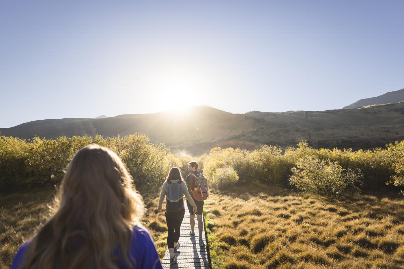 Photo from the point of view walking along the Glenorchy walkway with mountains and the rising sun ahead