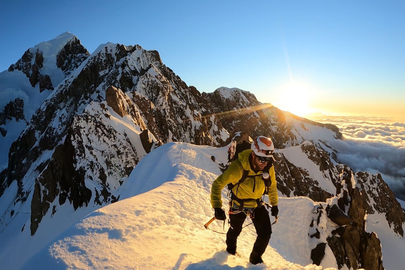 Mountaineer Hamish Fleming summiting mountain at sunrise