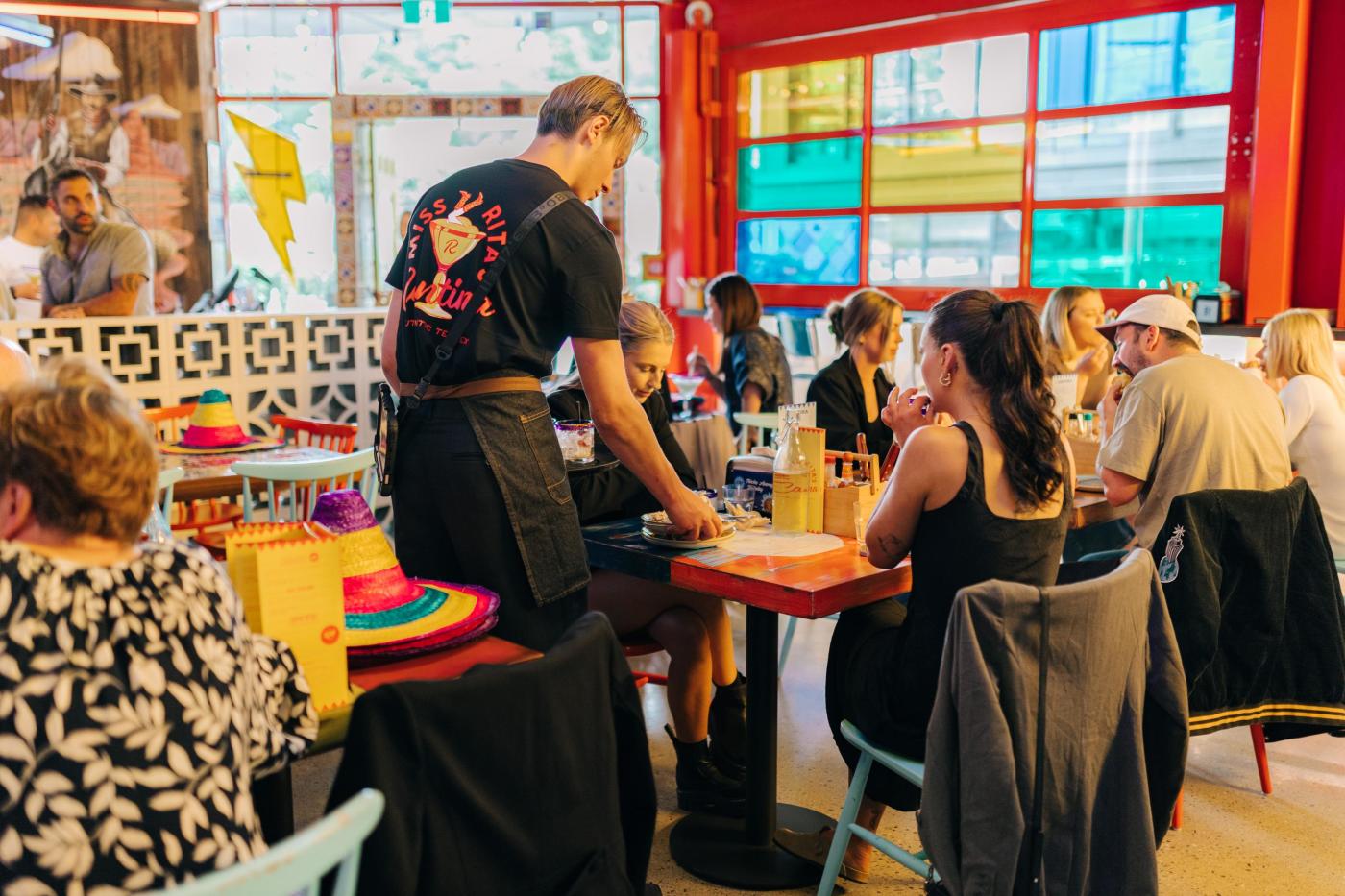 Person serving a table in a colourful Mexican themed restaurant