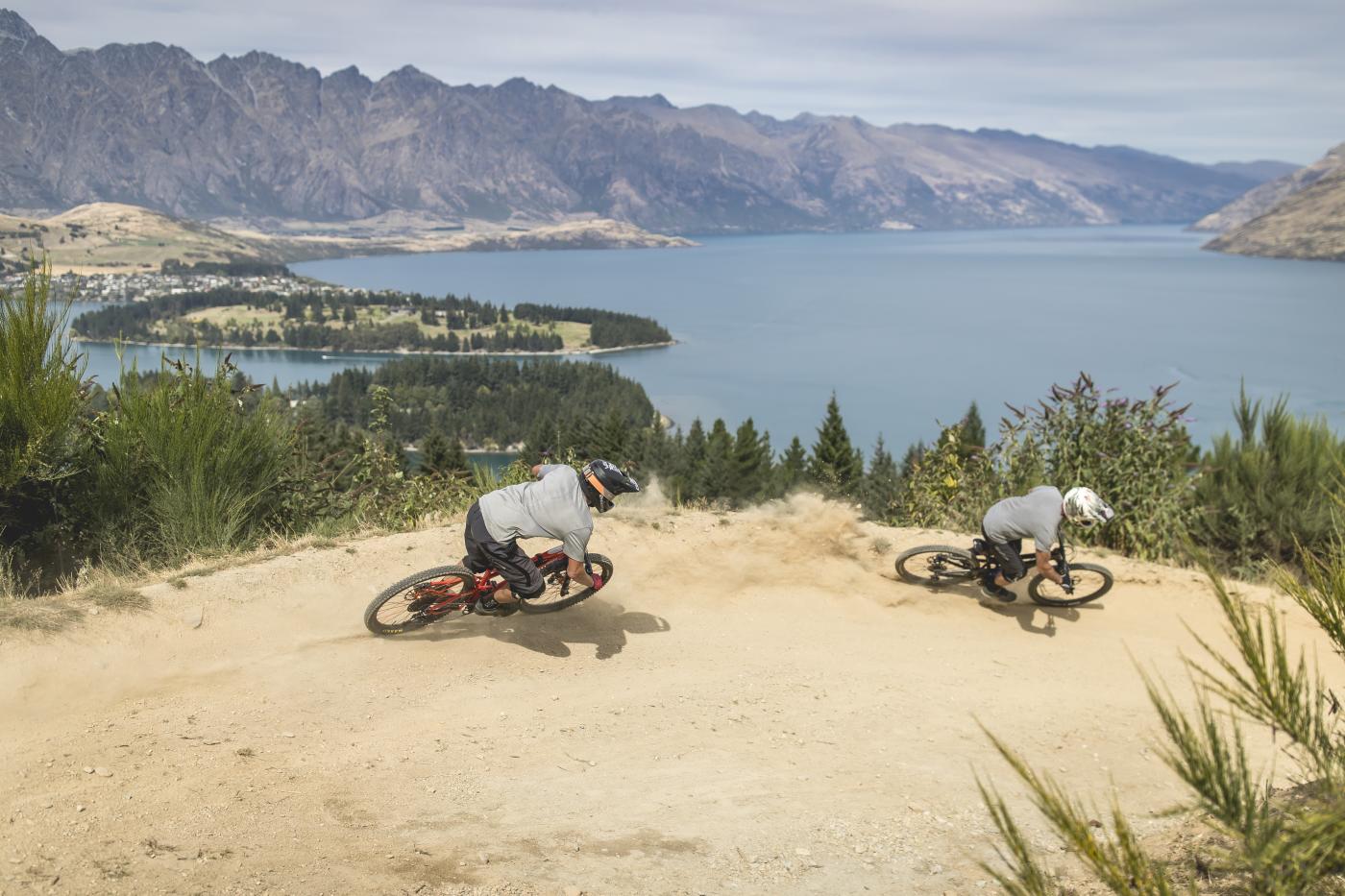 Bikers riding Queenstown Bike Park in Queenstown with Remarkables Mountains in the background