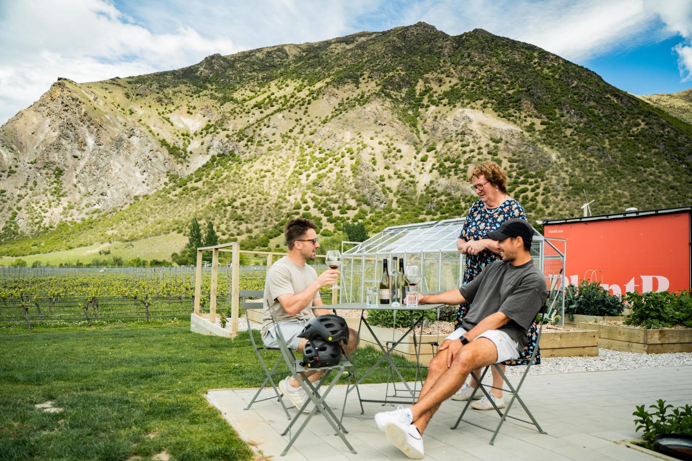 People enjoying a wine at ta table with mountains in the background