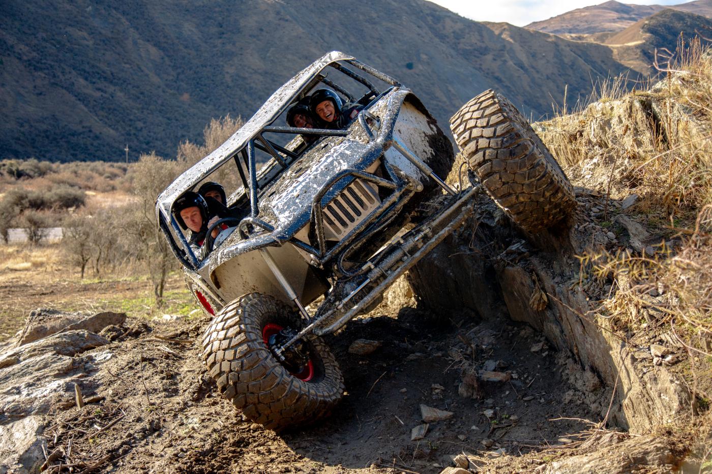 Group of people on uneven terrain in an Oxbow off-roader vehicle