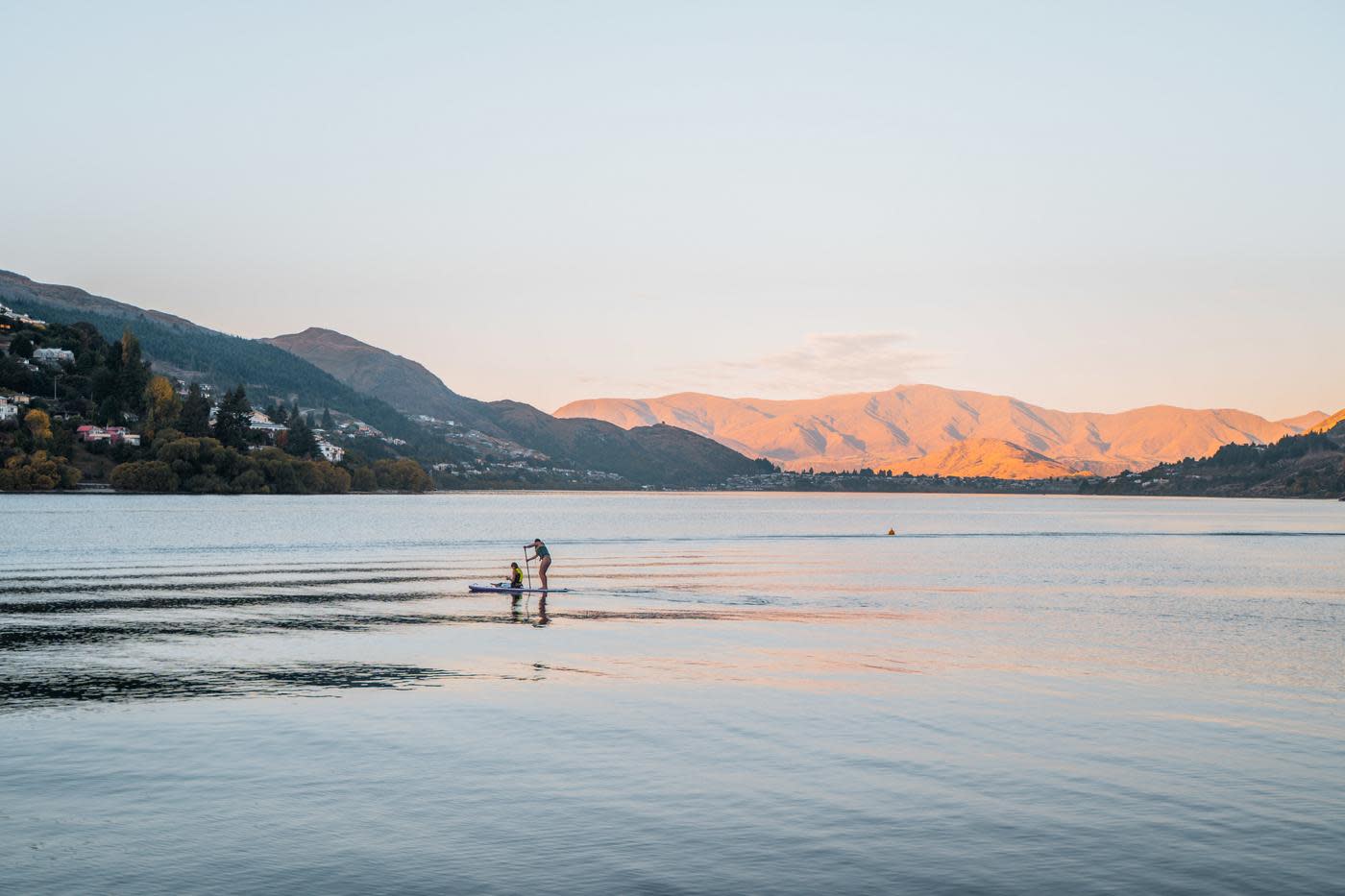 Paddleboarders in the middle of the lake at dusk