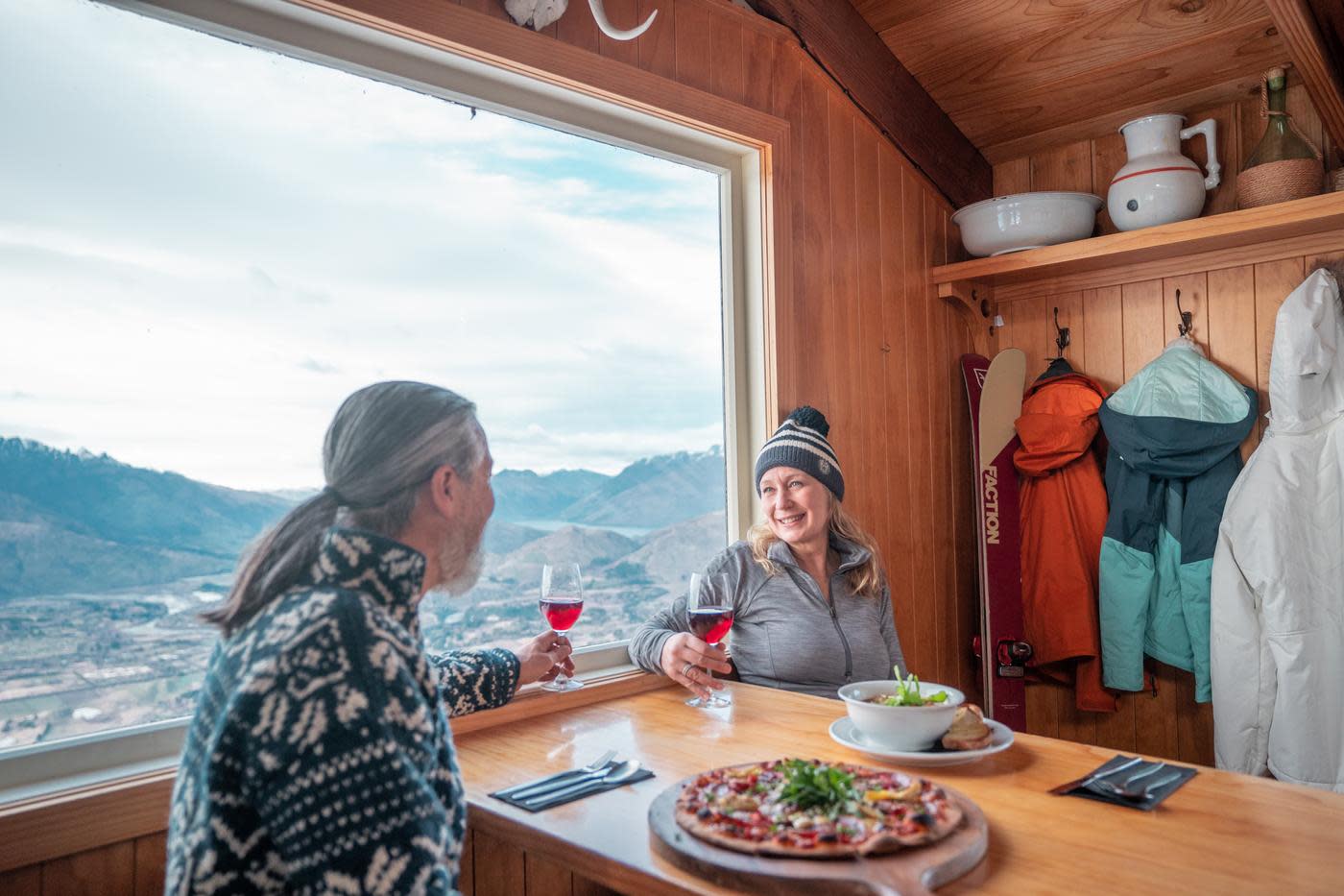 Couple enjoying pizza and wine at Heidi's Hut on Coronet Peak