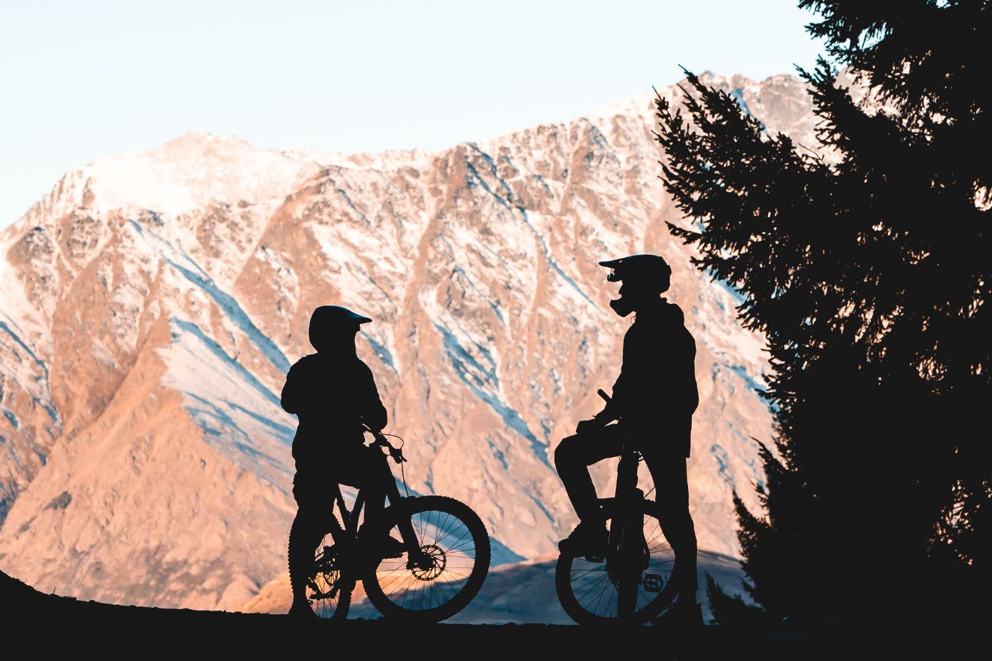 Mountain bikers pausing for a break next to The Remarkables mountain range in winter