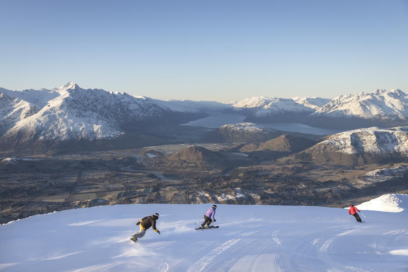 Skiers at Coronet Peak with wide view of snow-capped mountains