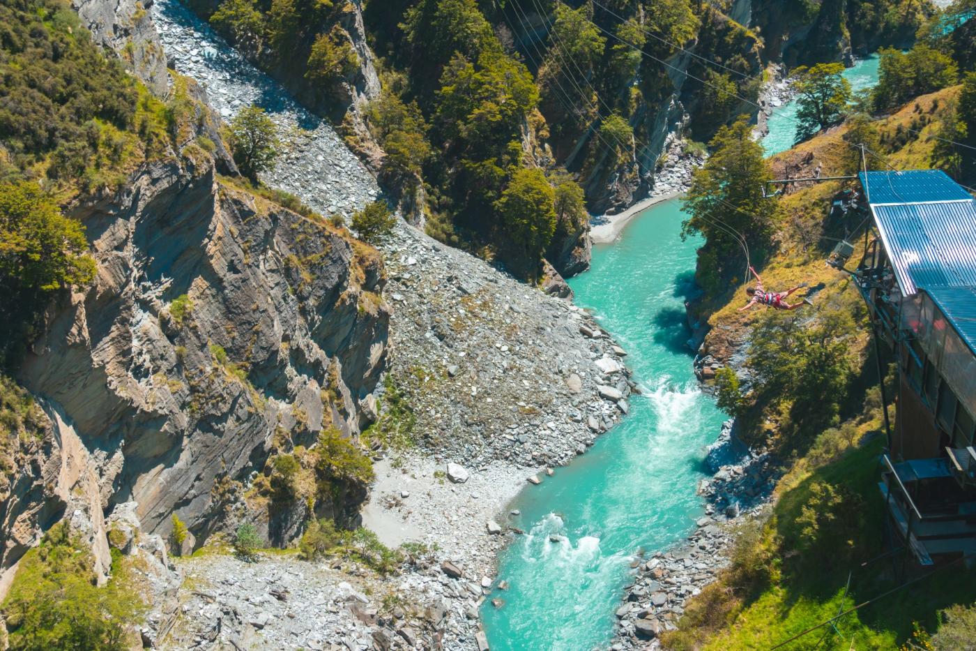 Far shot of a person doing the Canyon Swing with a river below