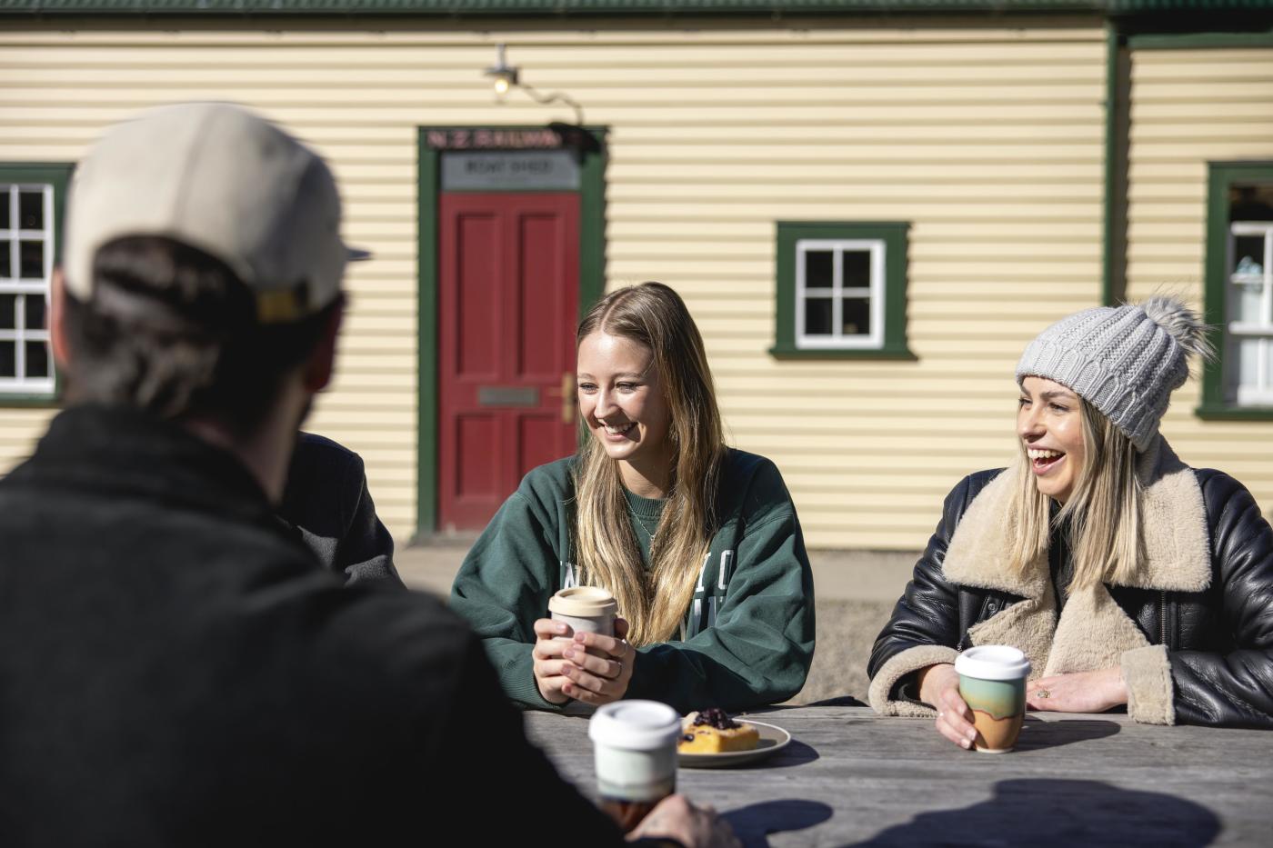 People holding keep cups outside The Boat Shed Cafe and Bistro