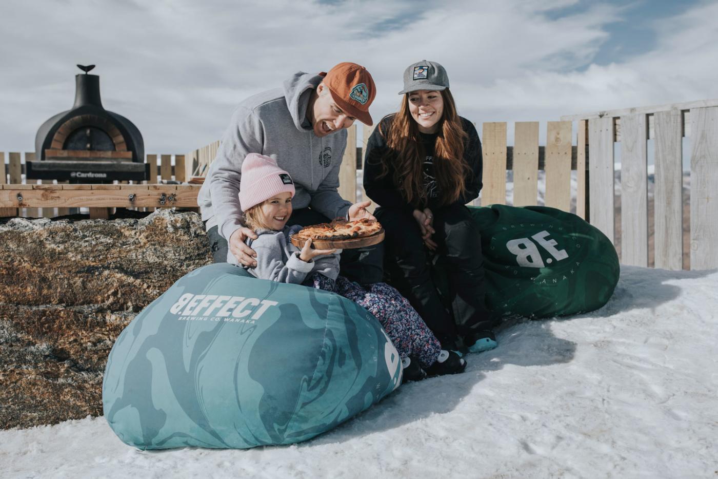 Family sitting on bean bags eating a pizza at Cardrona Alpine Resort ski area