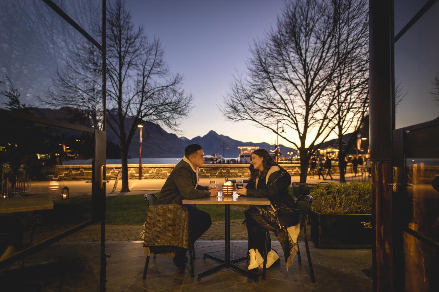 Couple sitting outside The Lodge Bar enjoying a drink on a winter event at sunset