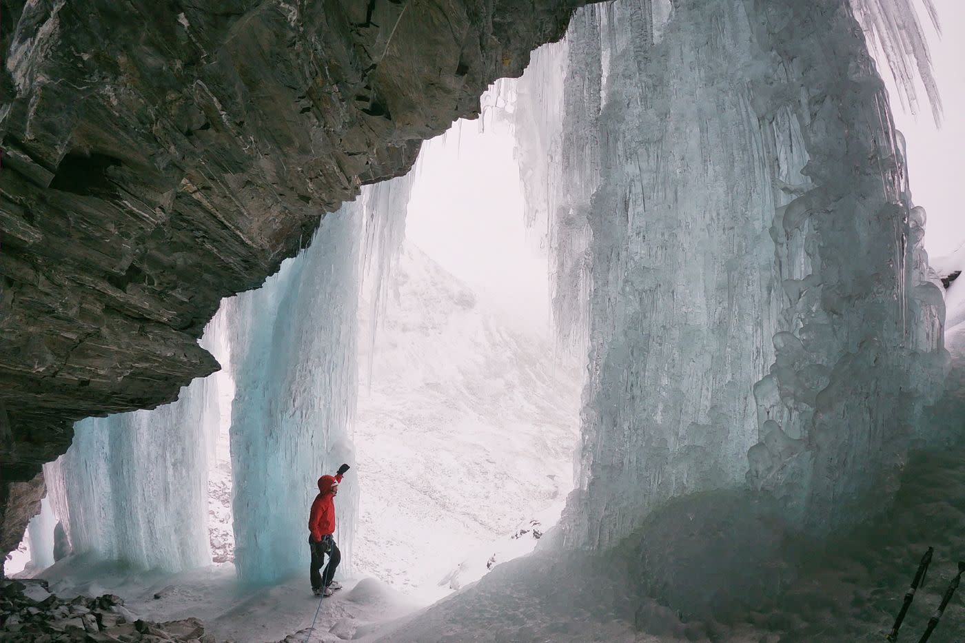 Ice climber standing next to ice face